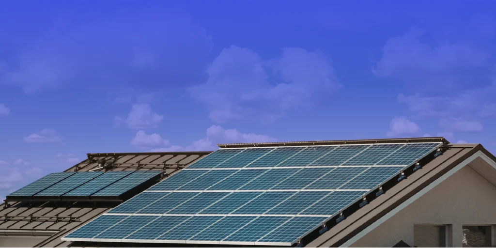 Instalación de placas solares sobre el tejado de una vivienda unifamiliar bajo un cielo azul con nubes